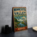 A vintage-style sign for the Minnesota Valley National Wildlife Refuge, featuring an illustration of a bird and a river, is displayed on a gray concrete surface.
