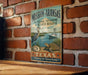 A vintage-style metal sign for Mission Aransas National Estuarine Research Reserve in Texas, featuring illustrations of a heron and a turtle, mounted on a brick wall.