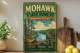 a vintage-style metal sign for the Mohawk State Forest in Connecticut, with a scenic landscape of pine trees, a lake, and mountains in the background.