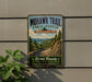 A vintage-style metal sign for the Mohawk Trail in Massachusetts, featuring a scenic mountain landscape with a winding road.