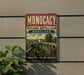 A vintage metal sign with the text "MONOCACY NATIONAL BATTLEFIELD MARYLAND" and an image of a cannon and a bridge, mounted on a wall.