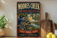 A vintage-style metal sign for Moore's Creek National Battlefield, featuring a painting of soldiers in historical attire and a banner that reads "Courage - Heritage - Freedom - North Carolina".
