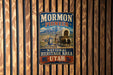 A vintage-style metal sign with the text "MORMON PIONEER NATIONAL HERITAGE AREA UTAH" displayed on a wooden wall.