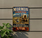 A vintage-style metal sign for the Mormon Pioneer National Heritage Area in Utah, featuring a wagon train and a mountain landscape.