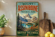 A vintage-style sign for Mount Assiniboine Provincial Park in British Columbia, Canada, featuring a scenic mountain landscape with a lake and pine trees.