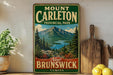 Mount Carleton, a scenic mountain range in New Brunswick, Canada, is depicted on a vintage-style sign.