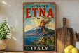 A vintage-style poster advertising Mount Etna, Italy, featuring a scenic landscape with a volcano, cacti, and a coastal town.