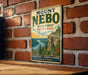 A vintage-style metal sign with the text "Mount Nebo State Forest Maryland" and "Scenic Beauty - Outdoor Adventure Explore & Enjoy!" is displayed on a brick wall.