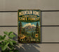 A vintage metal sign for the Mountain Home State Forest in California, featuring a scenic mountain landscape with pine trees and a lake.