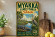 A vintage-style metal sign for the Myakka State Forest in Florida, featuring an illustration of a large alligator and a tall bird, with a scenic landscape in the background.