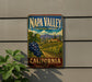 A vintage-style sign for Napa Valley, California, featuring a vineyard landscape with grapes and buildings in the background.