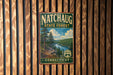 A vintage metal sign for the Natchaug State Forest in Connecticut, featuring a scenic landscape with pine trees and a lake.