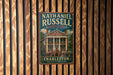 A vintage-style metal sign for Nathaniel Russell House in Charleston, South Carolina, mounted on a wooden wall.