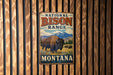 A vintage metal sign for the National Bison Range in Montana, featuring an illustration of a bison in a grassy field with mountains in the background.