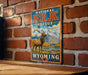 A vintage-style sign for the National Elk Refuge in Wyoming, featuring an illustration of a majestic elk standing in a scenic landscape with mountains in the background.