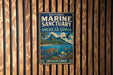 A vintage metal sign for the National Marine Sanctuary of American Samoa, featuring an illustration of a tropical island, sea turtle, and fish.
