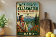 A vintage-style metal sign for Nez Perce National Forests in Idaho, featuring an illustration of a Native American man in traditional clothing standing in a scenic forest landscape.