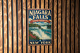 A vintage-style metal sign for Niagara Falls, the National Heritage Area in New York, is displayed on a wooden wall.