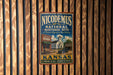A vintage-style metal sign for the Nicodemus National Historic Site in Kansas, featuring an illustration of a building and a church.