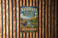 A vintage metal sign for Niobrara Valley Preserve in Nebraska, featuring a buffalo in a grassy field with a river and mountains in the background.