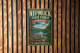 A vintage metal sign for the Nipmuck State Forest in Connecticut, featuring a scenic landscape with a lake and pine trees.