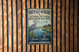 A metal sign with text and an illustration of a bird standing in a grassy area near a body of water, mounted on a wooden wall.