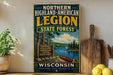 A vintage-style sign for the Northern Highland-American Legion State Forest in Wisconsin, featuring a scenic illustration of a lake, forest, and canoe.
