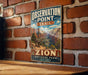 A vintage-style metal sign for the Zion National Park in Utah, featuring a scenic illustration of the park's landscape.