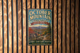 A vintage metal sign for October Mountain State Forest in Massachusetts, featuring a scenic mountain landscape and inviting visitors to explore the area.