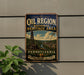 A vintage-style metal sign for the Pennsylvania Oil Region National Heritage Area, featuring an illustration of a coal mine and a river, mounted on a wall.