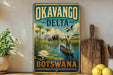 A vintage-style metal sign with the text "OKAVANGO DELTA BOTSWANA" and an illustration of a man in a boat on a river surrounded by wildlife, including elephants and a bird.