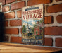a vintage metal sign for Old Sturbridge Village, with a brick wall and a wooden table in the background.