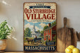 a vintage-style metal sign advertising "Old Sturbridge Village" in Massachusetts, with a picture of a horse-drawn carriage and a church.