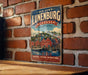 A vintage-style metal sign with the text "OLD TOWN LUNENBURG CANADA" and an illustration of a coastal town, hanging on a brick wall.