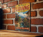 A vintage-style metal sign with the text "Old Town of Lijiang China" and an illustration of a traditional Chinese village with a bridge and waterway.