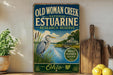 a vintage-style sign for the Old Woman Creek National Estuarine Research Reserve in Ohio, with a large blue bird illustration and a scenic background.