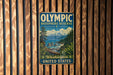 A vintage-style metal sign with the text "OLYMPIC BIOSPHERE RESERVE Washington United States" is displayed on a wooden wall.