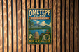 A vintage-style metal sign for Ometepe Island, Biosphere Reserve, and Nicaragua, featuring a tropical landscape with a mountain, palm trees, and a statue.