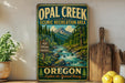 A vintage-style metal sign for Opal Creek Scenic Recreation Area in Oregon, featuring a mountain landscape with a river flowing through it.