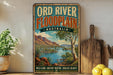 A vintage-style poster advertising the Ord River Floodplain in Australia, featuring a scenic landscape with mountains, a river, and lush vegetation.