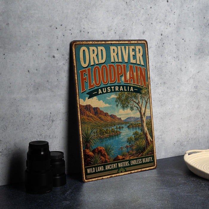A vintage-style sign for the Ord River Floodplain in Australia, featuring a scenic landscape with mountains, a river, and palm trees.