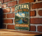 A vintage metal sign for the Ottawa National Forest in Michigan, featuring a moose and a scenic landscape.