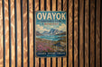 a vintage-style metal sign with a scenic landscape, mounted on a wooden wall.