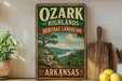 A vintage-style sign for the Ozark Highlands Heritage Landscape in Arkansas, featuring a scenic landscape with a river and mountains.