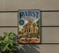 A vintage-style metal sign for Pabst mansion, a Milwaukee-based brewery, is displayed on a wall.