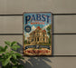 A vintage-style metal sign for Pabst mansion, a Milwaukee-based brewery, is displayed on a wall.