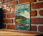 A vintage-style metal sign for Pancake Bay Provincial Park in Ontario, Canada, featuring a scenic landscape with pine trees, a beach, and a lake.
