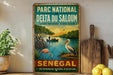 a vintage-style metal sign with a tropical scene depicting a flamingo, a boat, and a palm tree, along with text in French that reads "PARC NATIONAL DU DELTA DU SALOUM NATURE PRESERVEÉ, AVENIR ASSURE".
