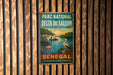 A vintage metal sign with a tropical scene of a flamingo, palm trees, and a boat on a river, hanging on a wooden wall.