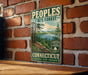 A vintage-style metal sign for the Connecticut State Forest, featuring a scenic landscape with pine trees, a lake, and mountains.